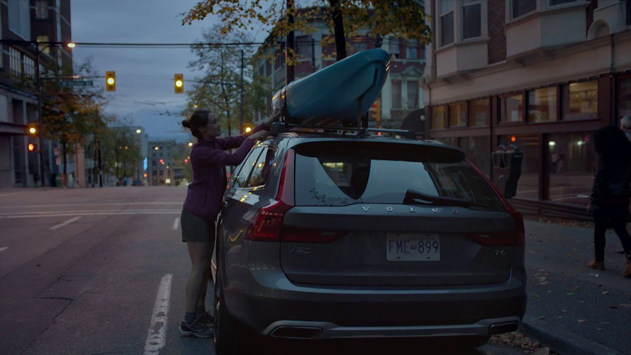 a woman putting a surfboard on the roof of a car