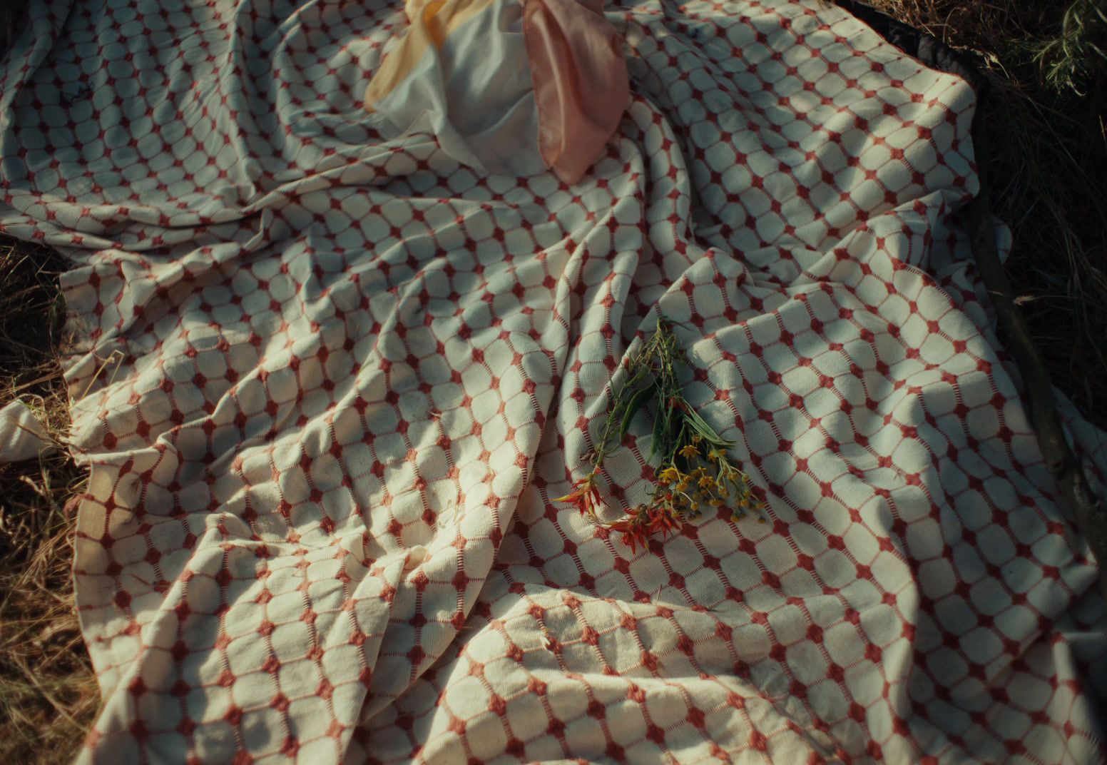 a red and white checkered blanket laying on the ground