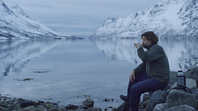 a man sitting on a rock next to a body of water