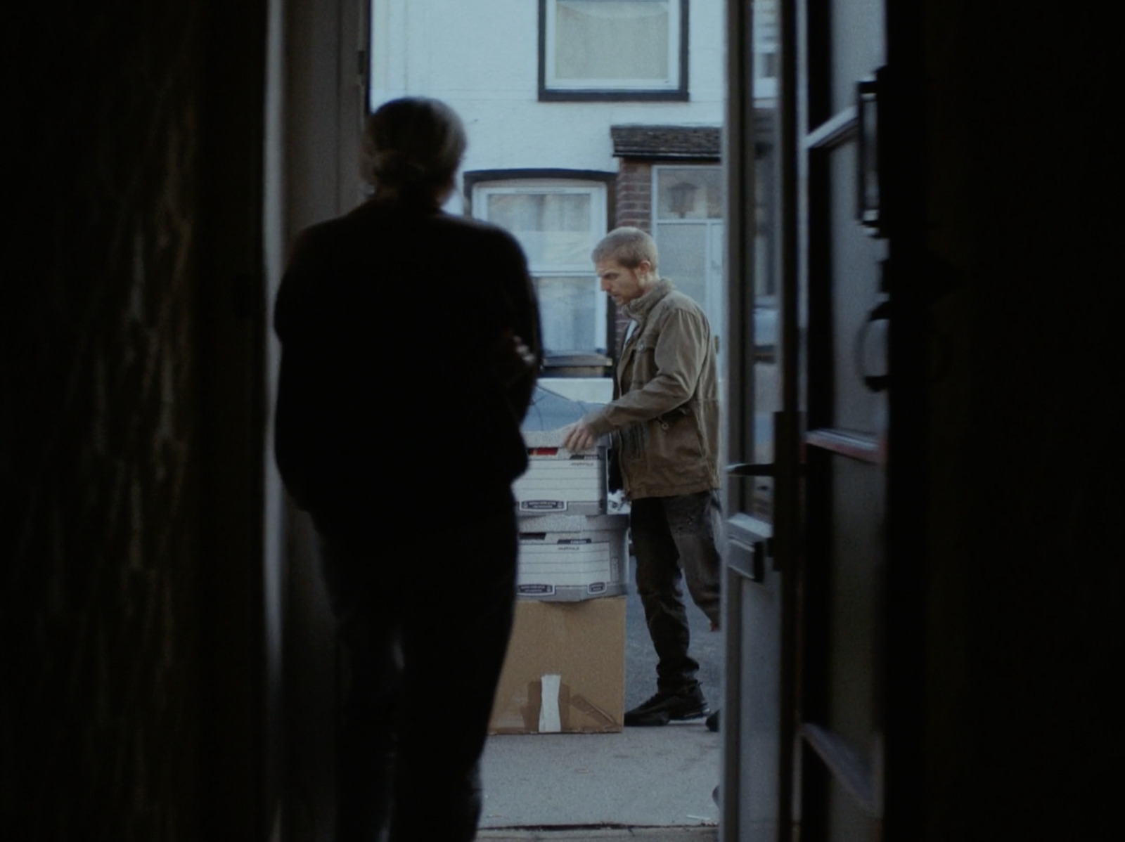 two men standing in a doorway looking at a box