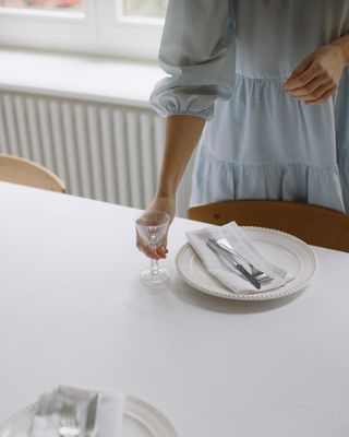 a woman standing at a table holding a glass