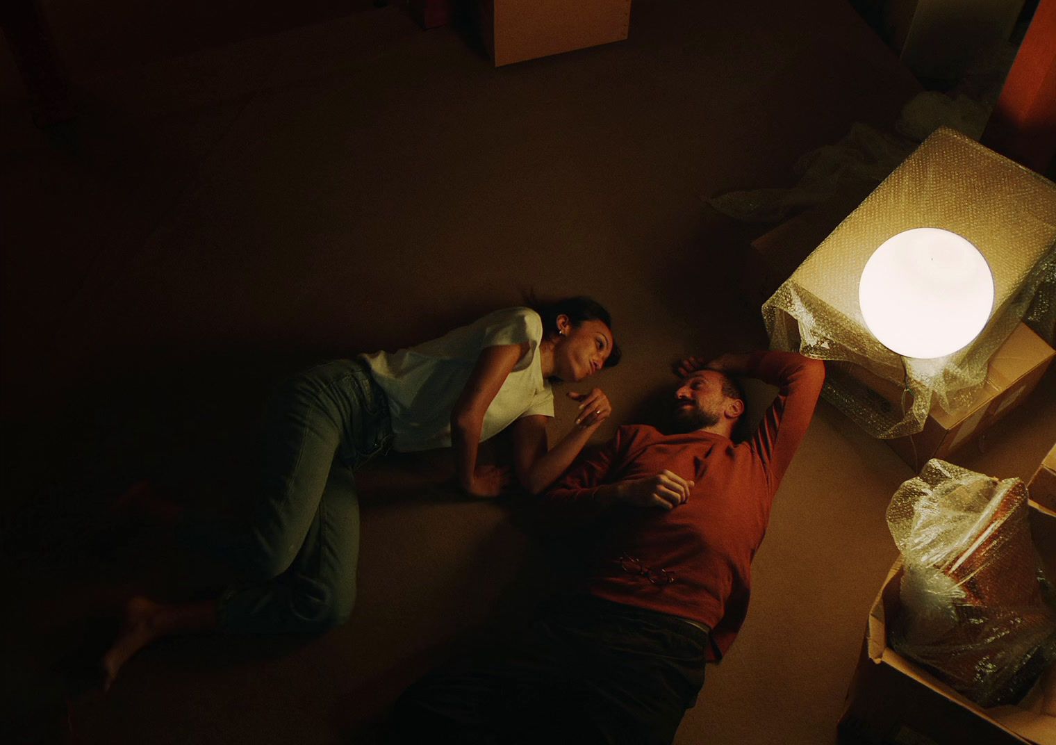 two people laying on the floor next to a lamp