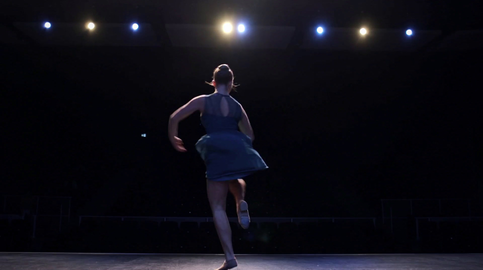 a woman in a blue dress is dancing on a stage