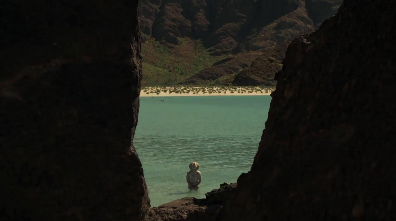 a person standing in a body of water with mountains in the background