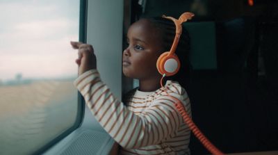 a little girl wearing headphones looking out a window