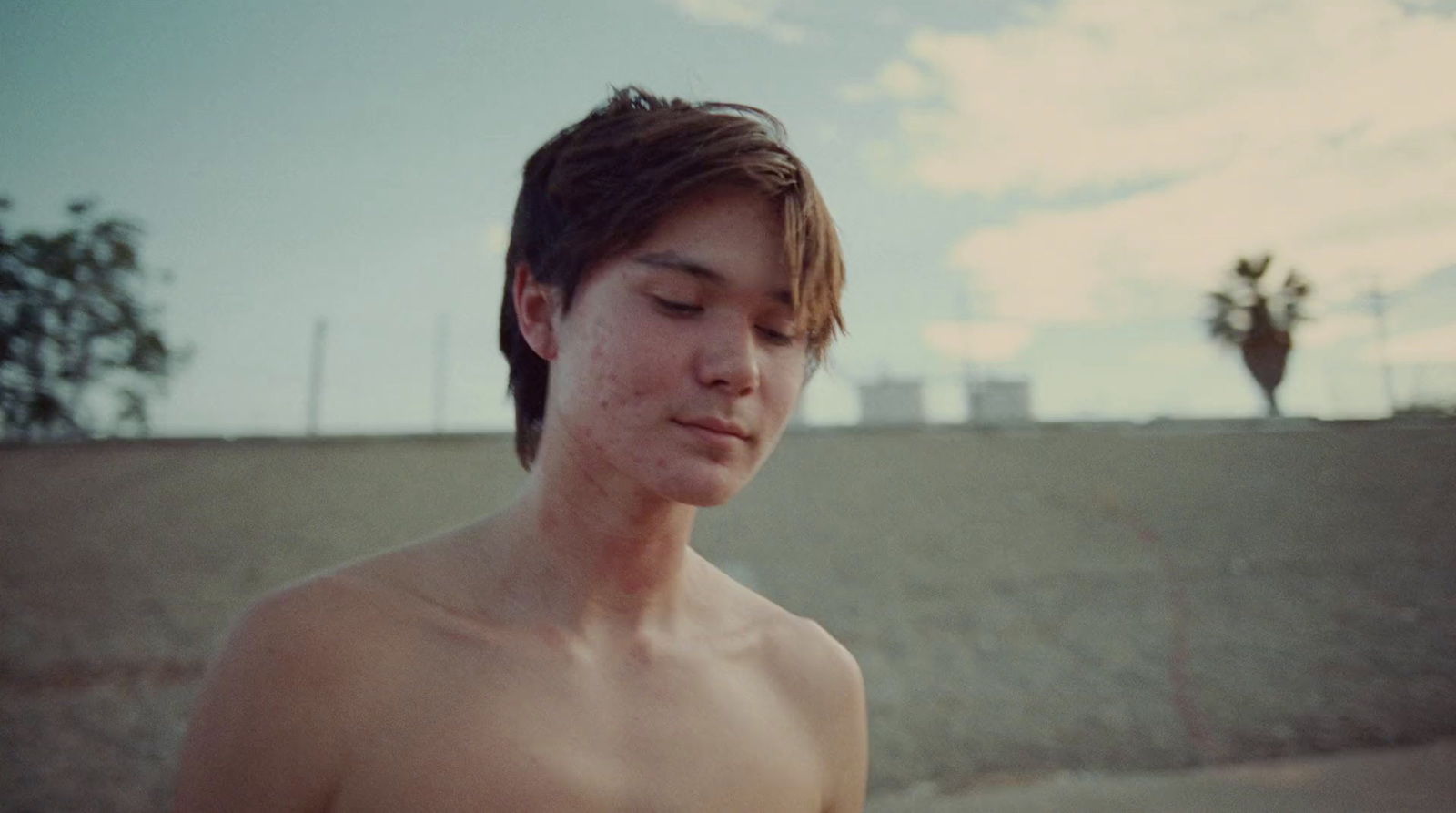 a shirtless young man holding a cell phone