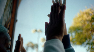 two hands reaching up into the air with trees in the background