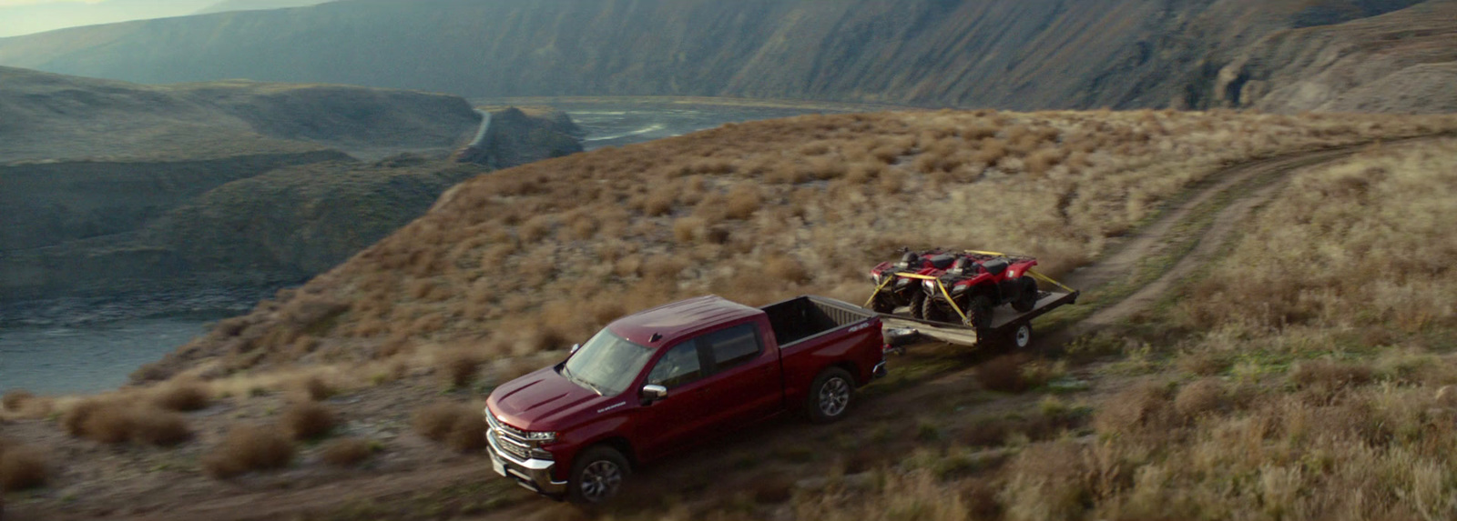 a red truck pulling a trailer down a hill