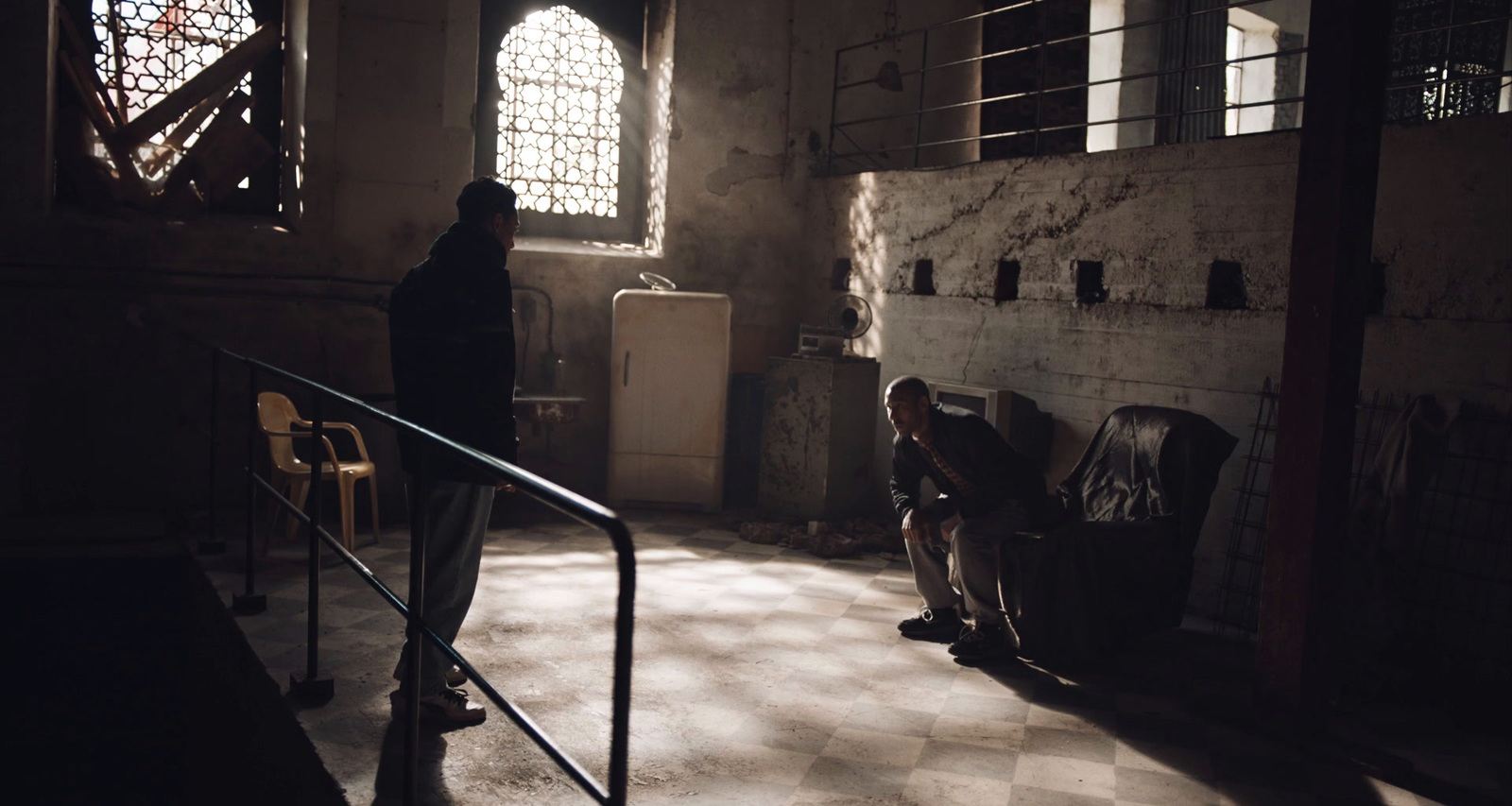 two people standing in a dark room with a checkered floor