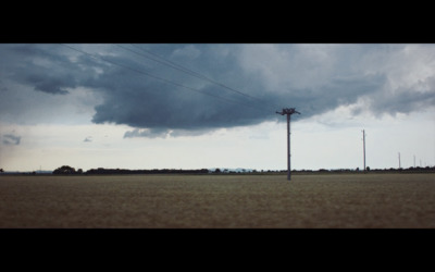 a large field with a telephone pole in the distance