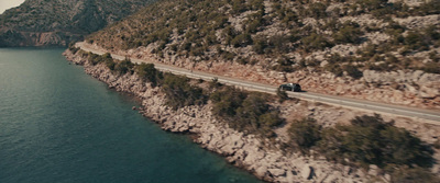 a car driving down a road next to a body of water