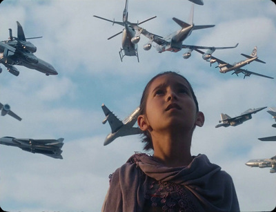 a boy looking up at a group of planes flying overhead