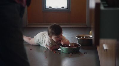 a baby is laying on the floor next to a bowl of food