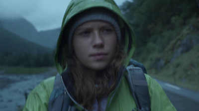 a woman in a raincoat standing on a road