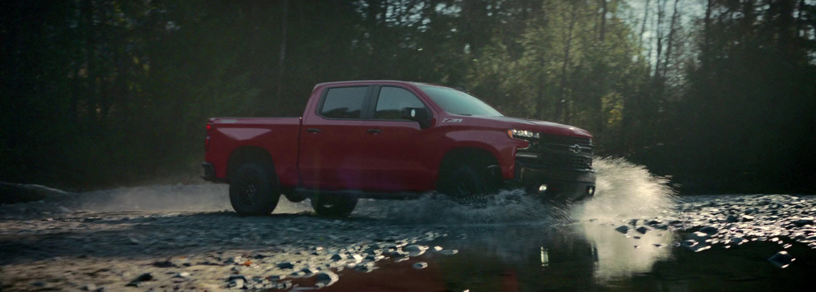 a red truck driving through a puddle of water