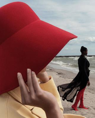 a woman in a red hat walking on the beach