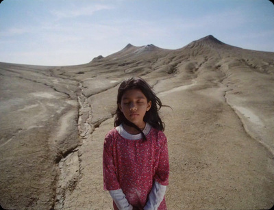 a little girl standing in the middle of a desert