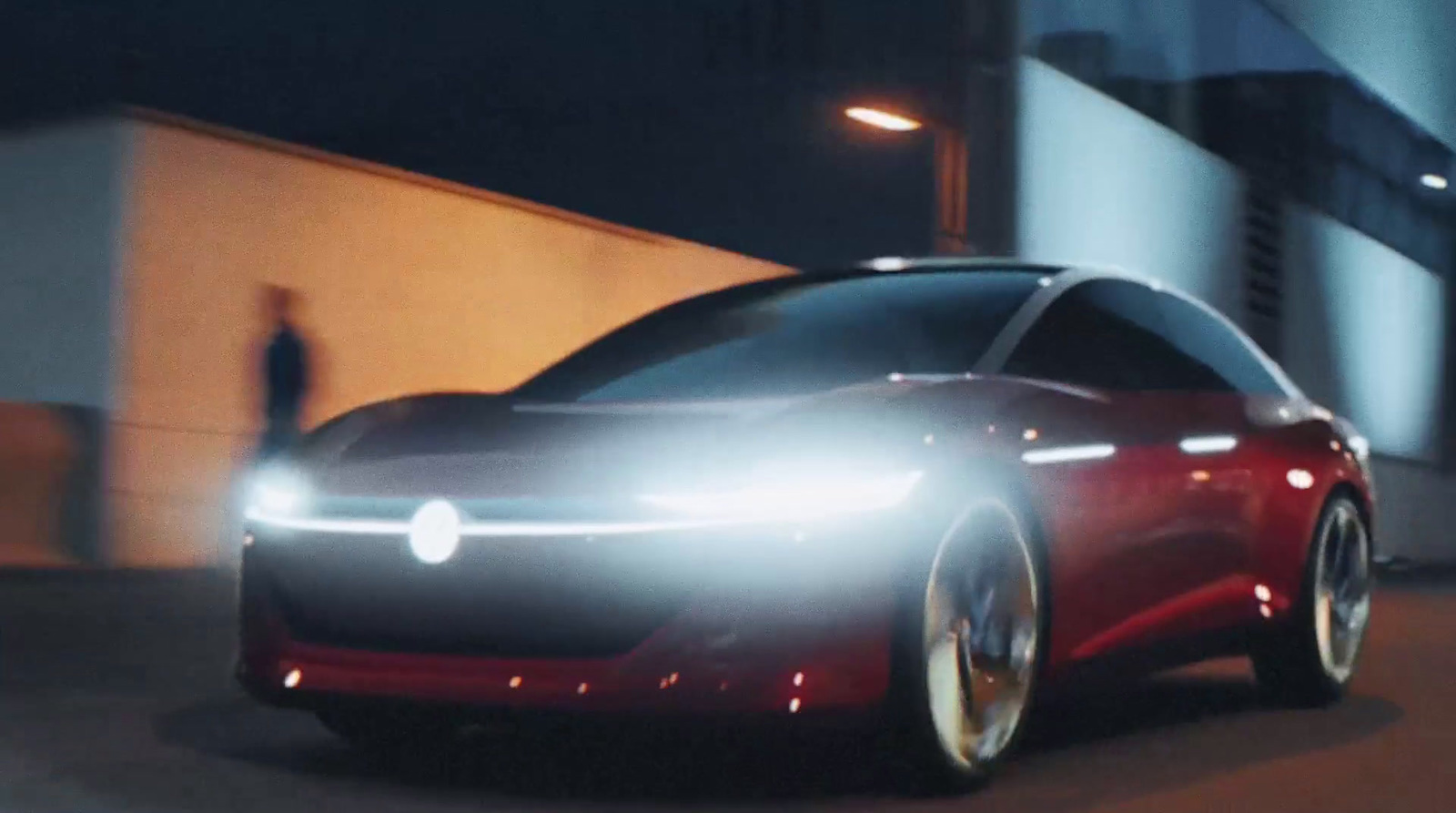 a red car driving down a street at night