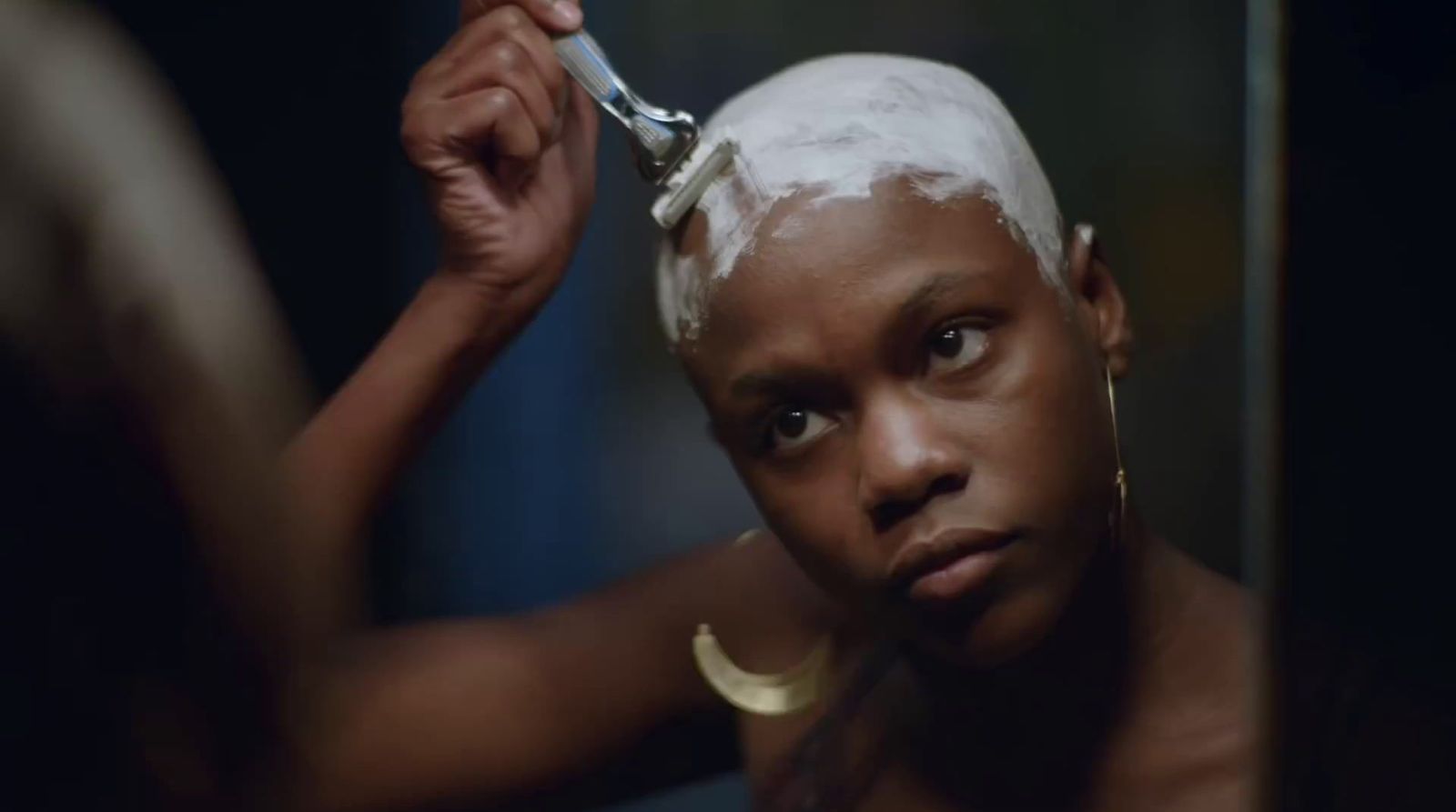 a woman is shaving her hair with a razor