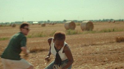 two people in a field with hay bales