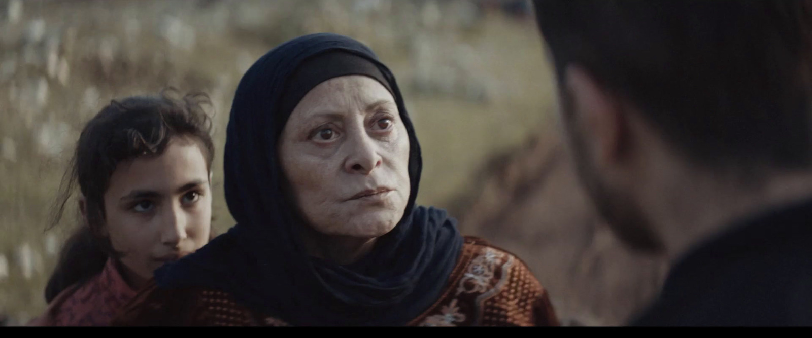 a woman in a headscarf looking at another woman