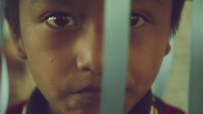 a young boy is looking through the bars of a jail cell