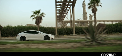 a white car driving down a street next to palm trees