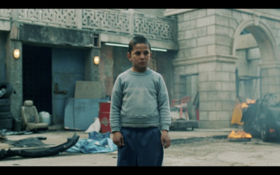 a young boy standing in front of a fire