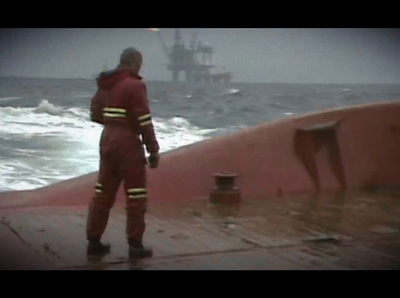 a man in a red suit standing on a boat in the ocean