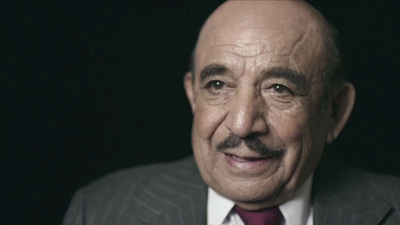 a man in a suit and tie smiling at the camera