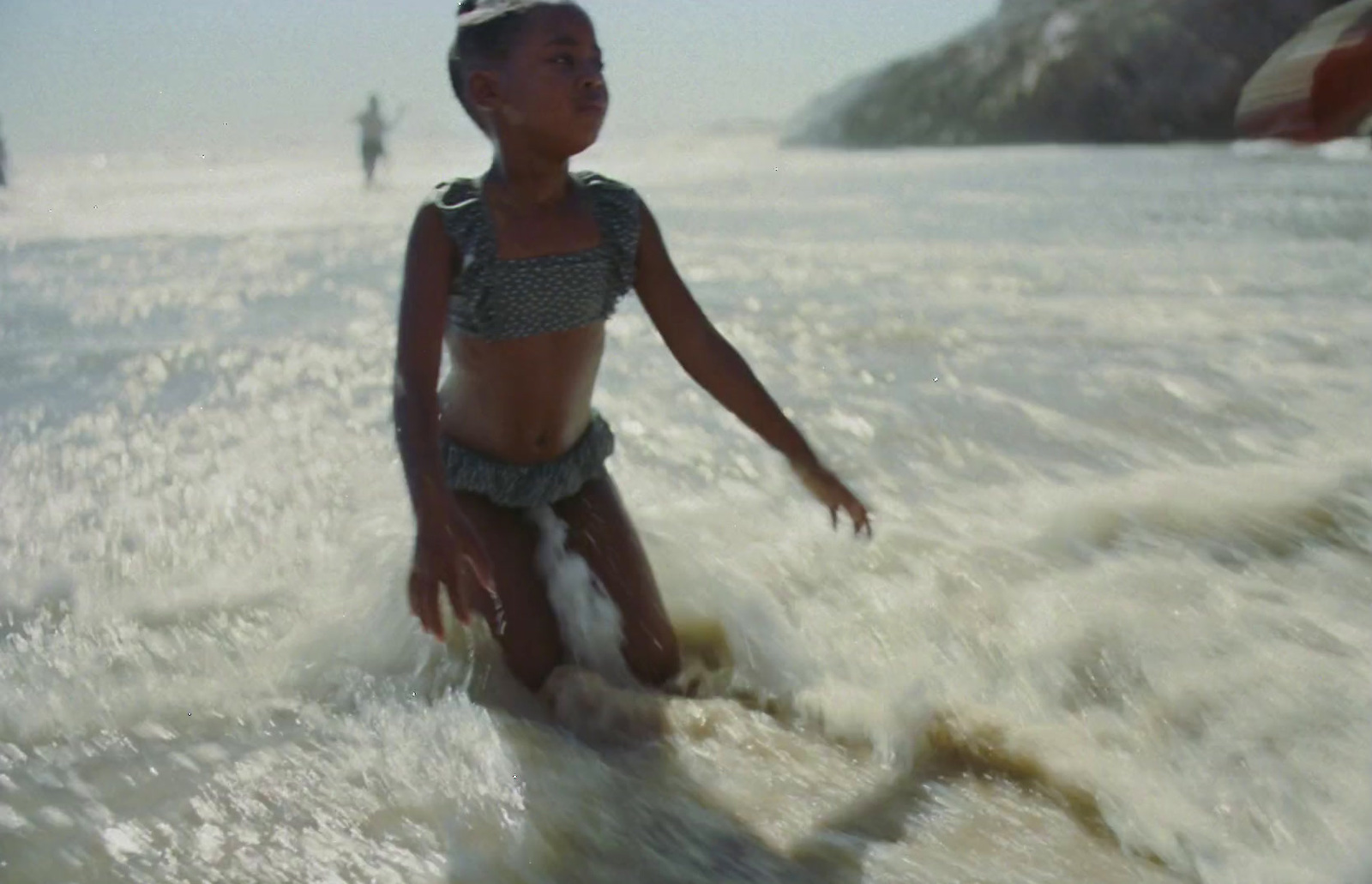 a young girl riding a wave on top of a surfboard