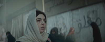 a woman wearing a headscarf standing in front of a wall