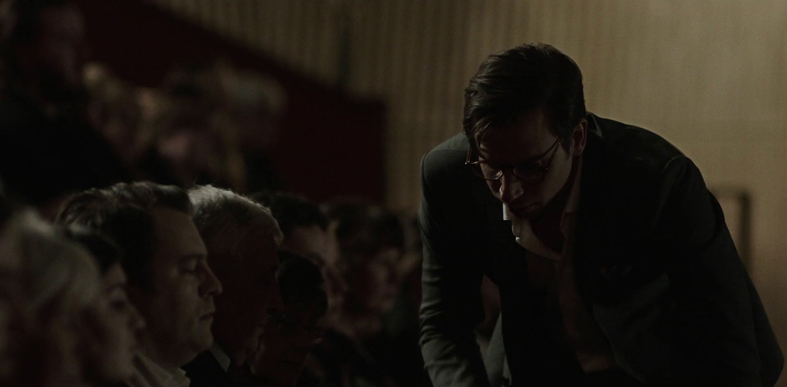 a man sitting in a crowd with his hand on his face