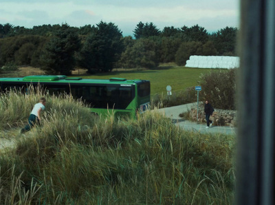 a green bus parked next to a lush green field