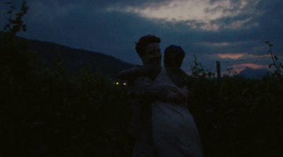 a man holding a woman in a field at night