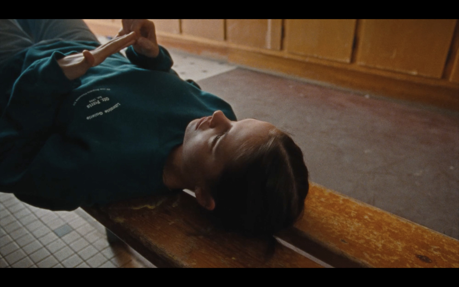 a young man laying on a wooden bench