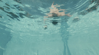 a person swimming in a pool with a frisbee