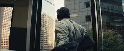 a man standing in front of a window looking out at the city