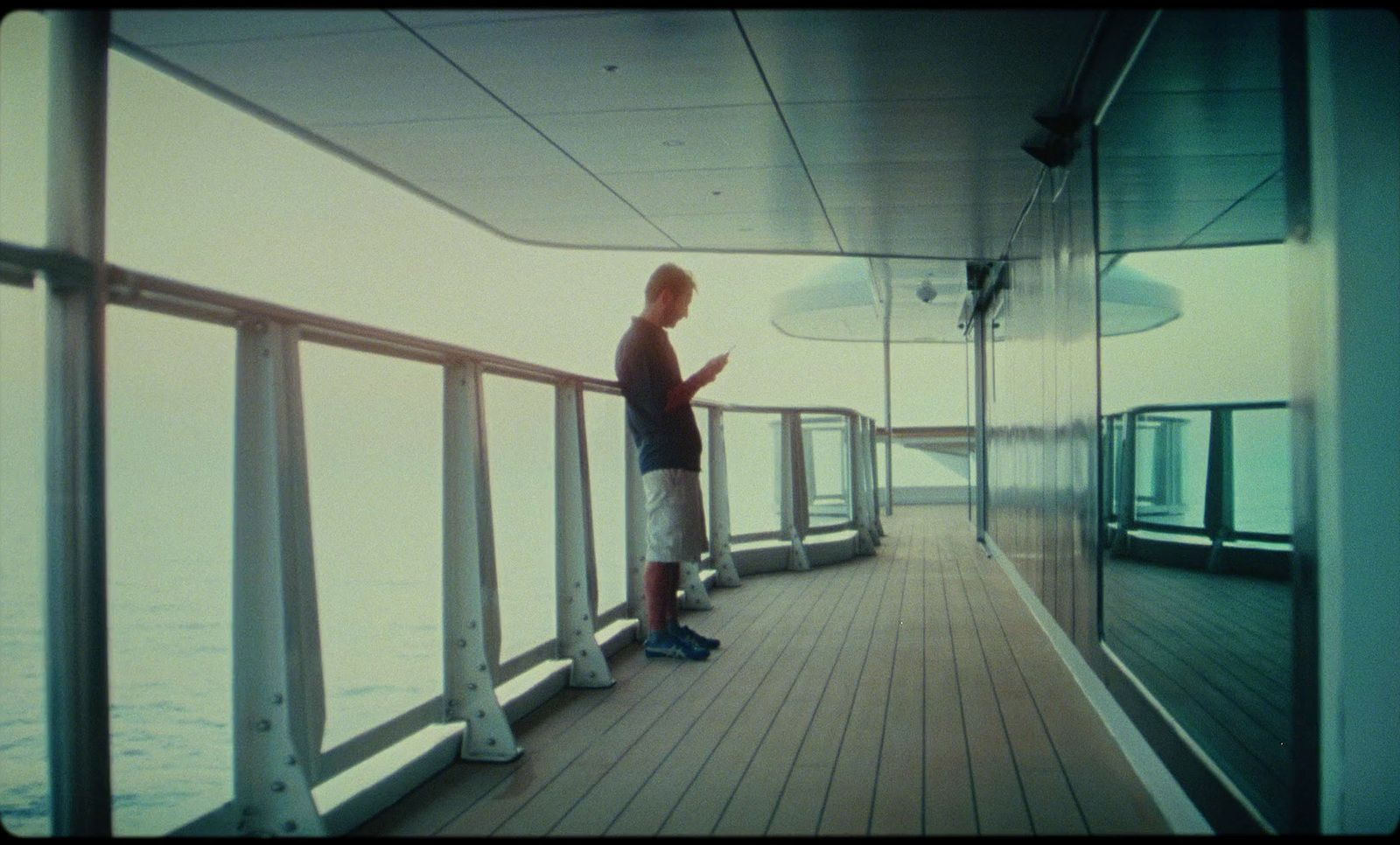 a man standing on a deck looking at his cell phone