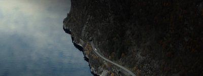 a car driving on a road next to a body of water