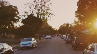 a group of cars driving down a street next to trees