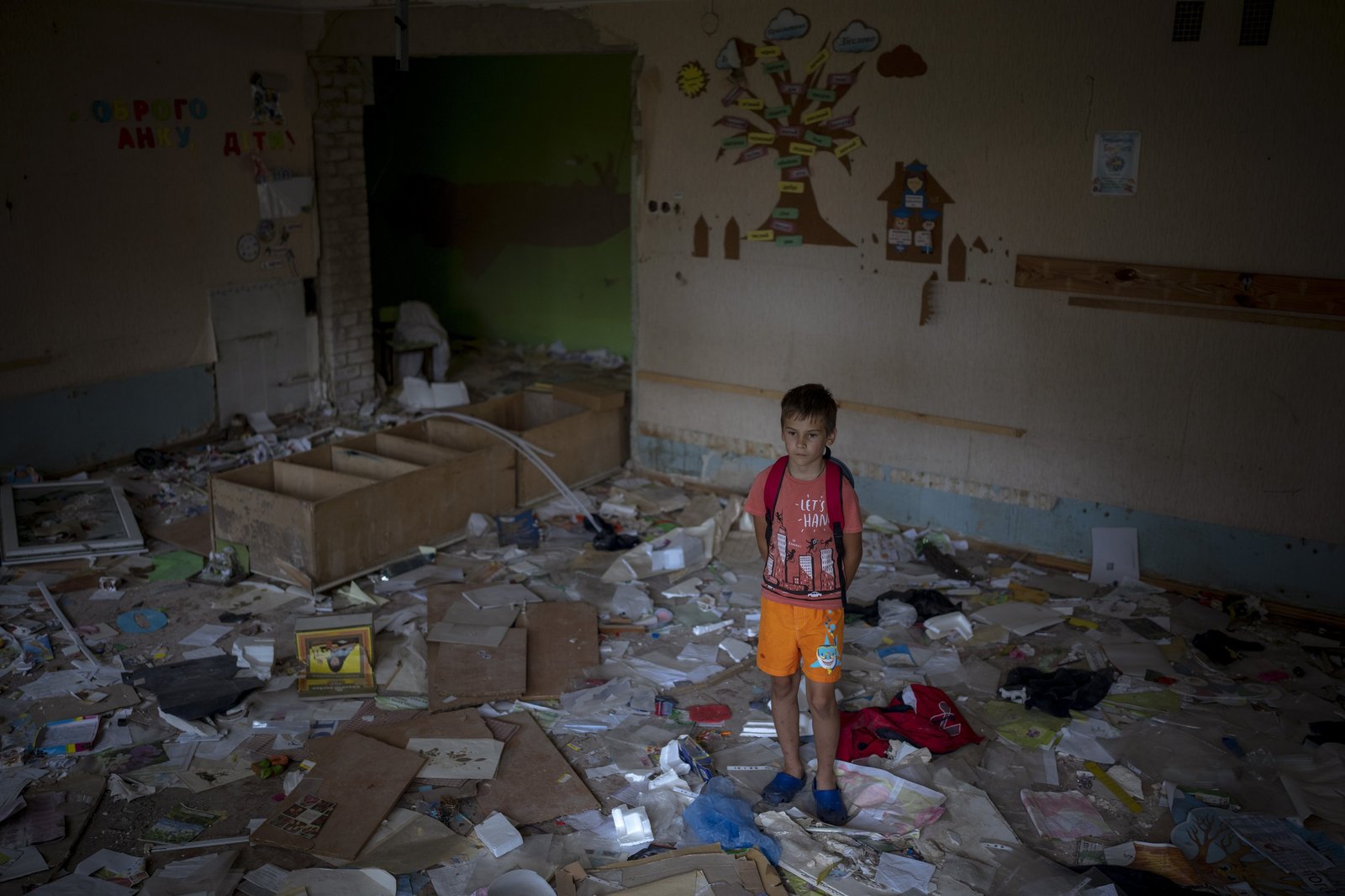 a young boy standing in a messy room