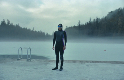 a man in a wet suit standing in front of a body of water