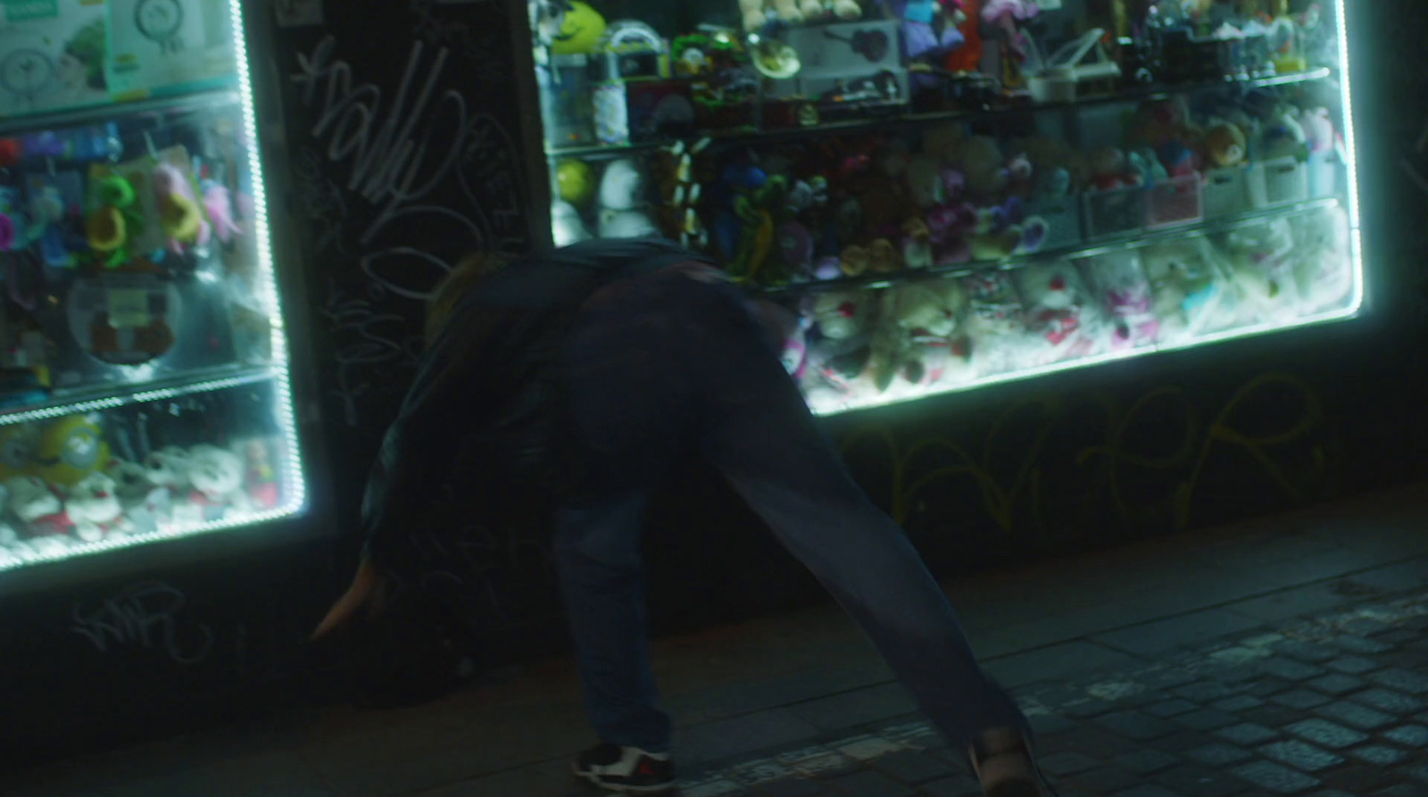 a man walking past a store filled with stuffed animals