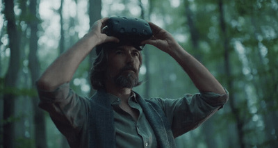 a man in a forest holding a camera up to his head