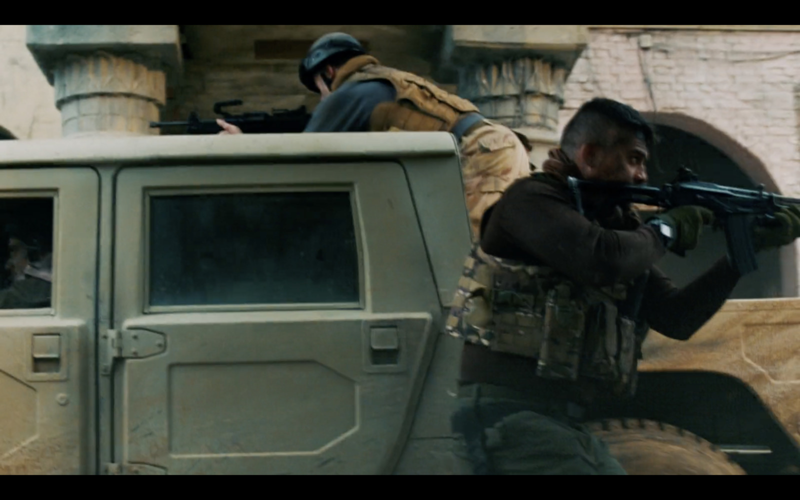 a man holding a gun while standing next to a truck