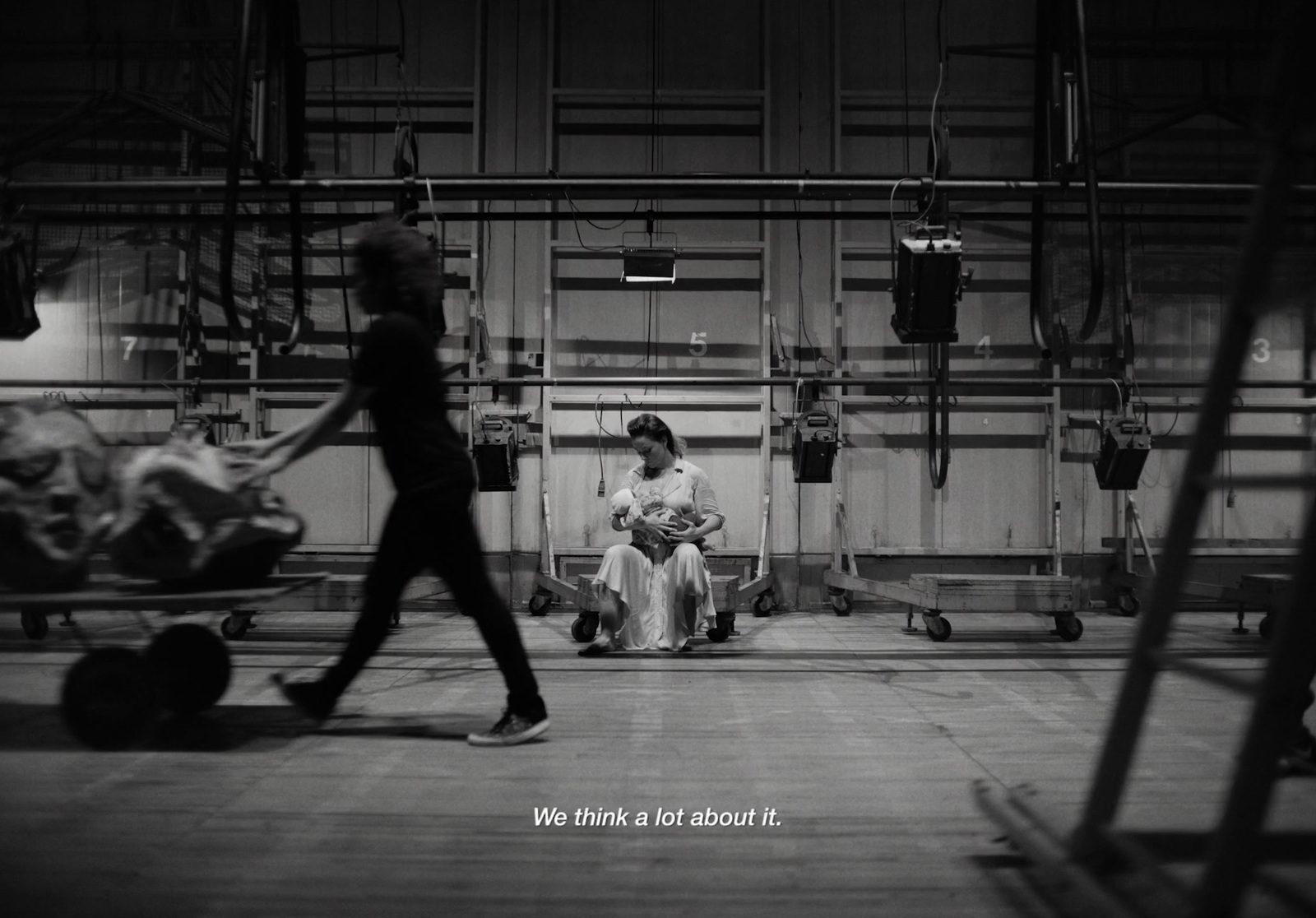 a black and white photo of a woman walking past a baby carriage