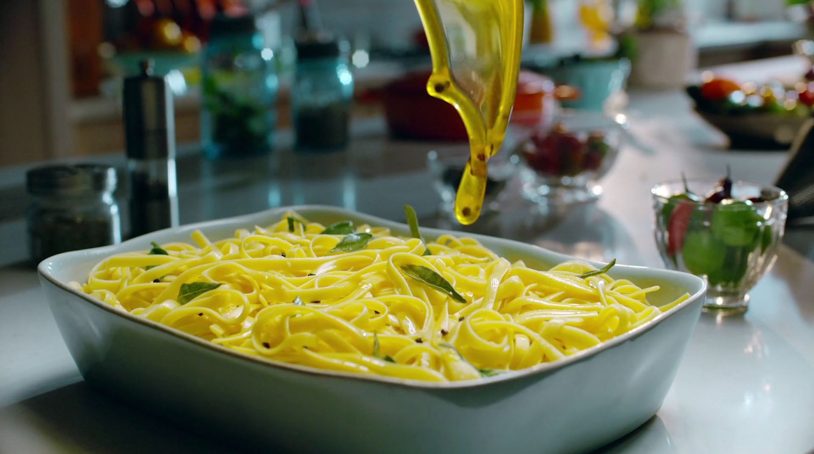 a bowl of pasta being poured with olive oil