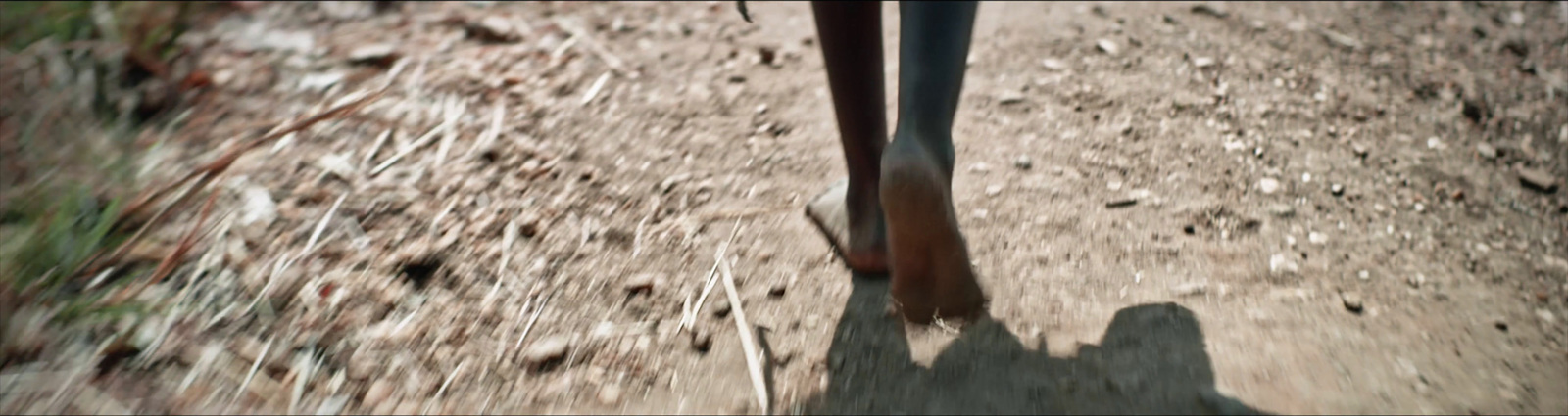 a person walking down a dirt road with their feet in the air