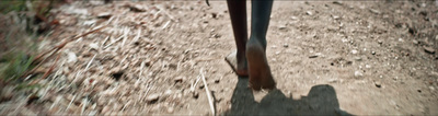 a person walking down a dirt road with their feet in the air